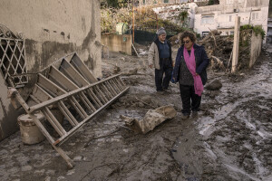 A man and a woman walk in the street the day after a landslide hit the Italian holiday island of Ischia, Southern Italy on November 27, 2022.