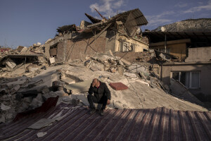 A man sits in the rubble of destroyed buildings in Hatay, Turkey on February 15, 2023. On February 6, 2023 a powerful earthquake measuring 7.8 struck southern Turkey killing more than 50,000 people.