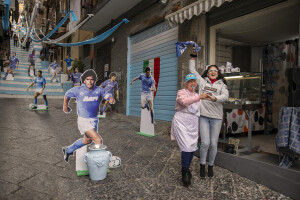 Two women dance near the blow-ups of the players of the Napoli team from the 90s at Spanish neighborhoods in Naples, Southern Italy on April 24, 2023.