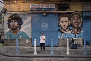 A little boy is seen near the mural depicting the Argentine soccer legend Diego Armando Maradona, the Georgian footballer and Napoli striker Khvicha Kvaratskhelia and the Nigerian footballer and Napoli striker Victor Osimhen in the Forcella district in Naples, Southern Italy on April 20, 2023.