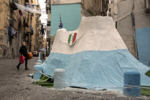 A woman walks near a paper mache volcano colored in white and blue to celebrate the victory of Napoli’s third championship at Spanish neighborhoods in Naples, Southern Italy on April 3, 2023.