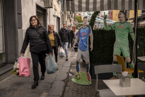 People walk near the giant prints of the Slovakian footballer and Napoli midfielder Stanislav Lobotka and Napoli and Italy goalkeeper Alex Meret in Sanità district in Naples, Southern Italy on April 6, 2023.