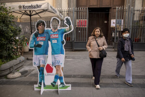 Two woman walk near the giant print of the Argentine soccer legend Diego Armando Maradona in the historical center of Naples, Southern Italy on April 6, 2023.