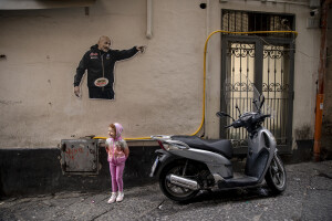 A little girl is seen near a photo of the coach of the Napoli football team Luciano Spalletti at the Spanish neighborhoods in Naples, Southern Italy on April 24, 2023.