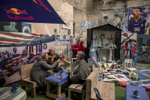 People drink a cocktail near an altar dedicated to the Argentine soccer legend Diego Armando Maradona is seen in the Spanish Quarter in Naples, Southern Italy on November 24, 2021. Diego Armando Maradona died on November 25 of last year and next November 25, 2021 will be the anniversary of his death.