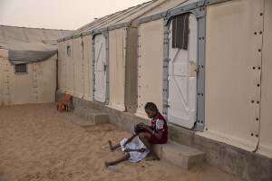 A little girl fixes her friend’s hair inside the Djougop temporary camp for internally displaced people who lost their homes due to coastal erosion in Saint-Louis, Senegal on December 13, 2023. At Djougop temporary camp located seven miles inland people live in small tents without bathrooms and electricity. Toilets and taps for running water are shared.