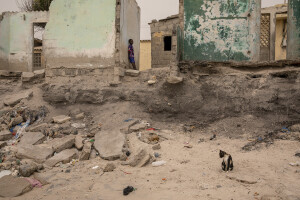 A child and a cat are seen near some houses heavily damaged by the sea in Bargny, Senegal on December 19, 2023. The coastal erosion began in the 1980s but worsened in the early 2000s. Storm surges have become more common and fiercer, like the passage of Hurricane Fred in the night of August 30, 2015. Bargny is currently losing three to four meters of coast each year.