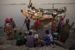 Women and children collect the day’s catch from a pirogue along the coast of the Senegal River in Saint-Louis, Senegal on December 11, 2023. Climate change also affects fishing, a key sector in Senegal which represents 3.2% of the country’s GDP (gross domestic product). The increase in water temperatures is having repercussions on marine ecosystems (changes in the migrations and habits of many fish species) which, in addition to the intensive fishing practiced by foreign fishing boats, is reducing the country’s fish resources. Furthermore, the advance of the sea is forcing many fishermen in Saint-Louis to leave their homes facing the sea and move inland: now to reach the sea and go fishing they have to face long and expensive journeys.
