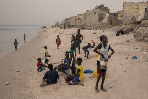 Children play on the beach near houses damaged by sea waves in Bargny, Senegal on December 19, 2023. The coastal erosion began in the 1980s but worsened in the early 2000s. Storm surges have become more common and fiercer, like the passage of Hurricane Fred in the night of August 30, 2015. Bargny is currently losing three to four meters of coast each year.