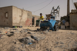 A child sitting on a wagon near a building slightly damaged by sea waves in the “Langue de Barbarie” in Saint-Louis, Senegal on December 12, 2023. The “Langue de Barbarie” is a thin, sandy peninsula located in western Senegal, where around 80,000 people live and is among the places most threatened by the rise in sea levels generated by climate change. The peninsula separates the Atlantic ocean from the final section of the Senegal river.