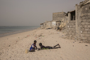 Two children play on the beach near houses damaged by sea waves in Bargny, Senegal on December 19, 2023. The coastal erosion began in the 1980s but worsened in the early 2000s. Storm surges have become more common and fiercer, like the passage of Hurricane Fred in the night of August 30, 2015. Bargny is currently losing three to four meters of coast each year.