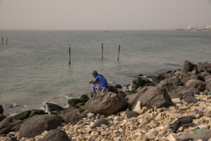 A man sits on the barrier built to stop the advance of the sea in Rufisque, Senegal on December 20, 2023.