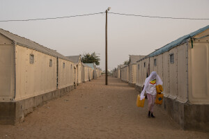 A girl with her face covered by a veil walks with water containers in her hands inside the Djougop temporary camp for internally displaced people who lost their homes due to coastal erosion in Saint-Louis, Senegal on December 13, 2023. At Djougop temporary camp located seven miles inland people live in small tents without bathrooms and electricity. Toilets and taps for running water are shared.