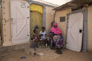 A mother with her two daughters eat outiside the tent where they live inside the Djougop temporary camp for internally displaced people who lost their homes due to coastal erosion in Saint-Louis, Senegal on December 13, 2023. At Djougop temporary camp located seven miles inland people live in small tents without bathrooms and electricity. Toilets and taps for running water are shared.