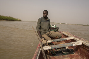 Mar Diop, 24 years old drives a pirogue headed towards the Doune Baba Dieye village in Saint-Louis, Senegal on December 12, 2023. Doune Baba Dieye was once a vibrant fishing community, but changing weather patterns and heavy rainfall in 2003 led to flooding inland and a rise in sea levels that have now submerged part of the village which today can only be reached by boats.