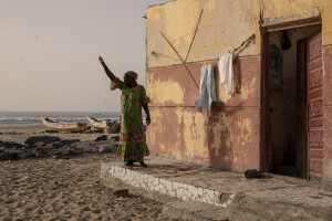 A woman is seen outiside the house where she lives in the “Langue de Barbarie” in Saint-Louis, Senegal on December 14, 2023. The Senegalese government is offering money to families who leave their homes by the sea and move to Djougop temporary camp, and then proceeds to demolish those homes. The “Langue de Barbarie” is a thin, sandy peninsula located in western Senegal, where around 80,000 people live and is among the places most threatened by the rise in sea levels generated by climate change. The peninsula separates the Atlantic ocean from the final section of the Senegal river.