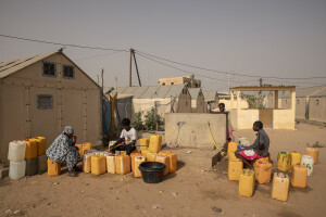 People fill water containers inside the Djougop temporary camp for internally displaced people who lost their homes due to coastal erosion in Saint-Louis, Senegal on December 13, 2023. At Djougop temporary camp located seven miles inland people live in small tents without bathrooms and electricity. Toilets and taps for running water are shared.