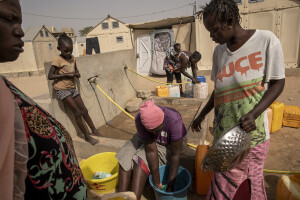 Women wash dishes and fill water containers inside the Djougop temporary camp for internally displaced people who lost their homes due to coastal erosion in Saint-Louis, Senegal on December 13, 2023. At Djougop temporary camp located seven miles inland people live in small tents without bathrooms and electricity. Toilets and taps for running water are shared.